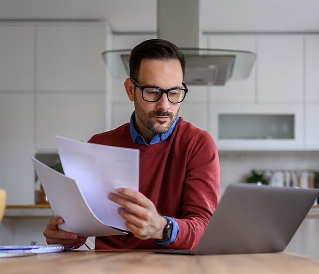 Ondernemer analyseert documenten en werkt achter laptop