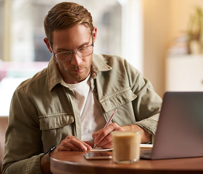 Ondernemer of student werkt in café met laptop en notities