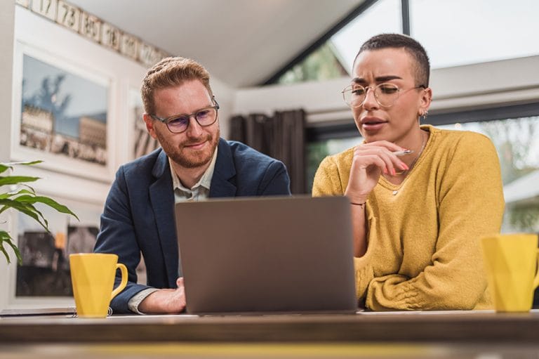 Ondernemer presenteert een voorstel aan klant terwijl ze samen naar de laptop kijken.