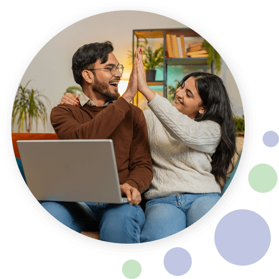 Man en vrouw zitten samen met een laptop op schoot en geven elkaar lachend een high five.